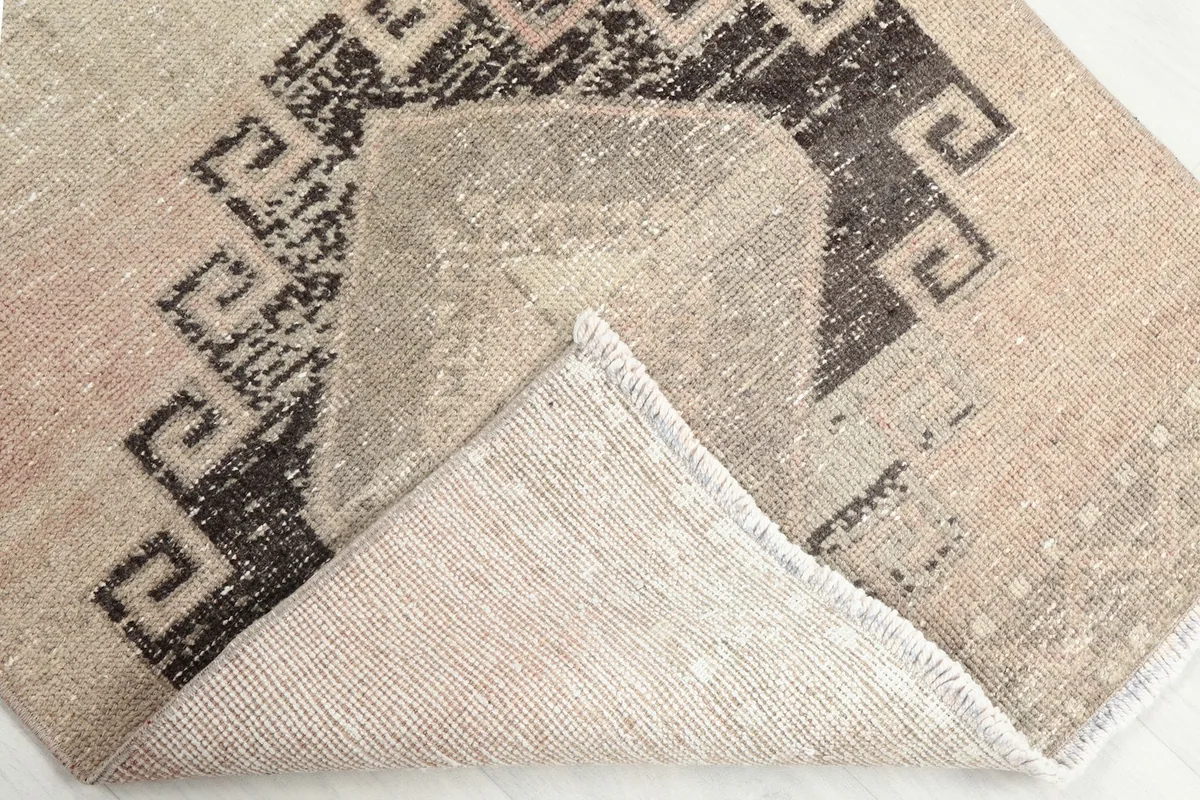 Corner of the rug folded back to reveal the cotton foundation and the reverse side of the hand-knotted construction.