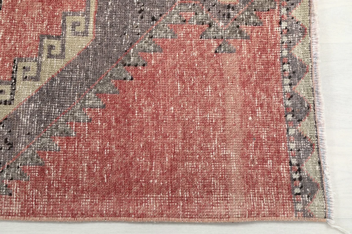 Detailed view of the rose field and faded charcoal border pattern at one end of the rug