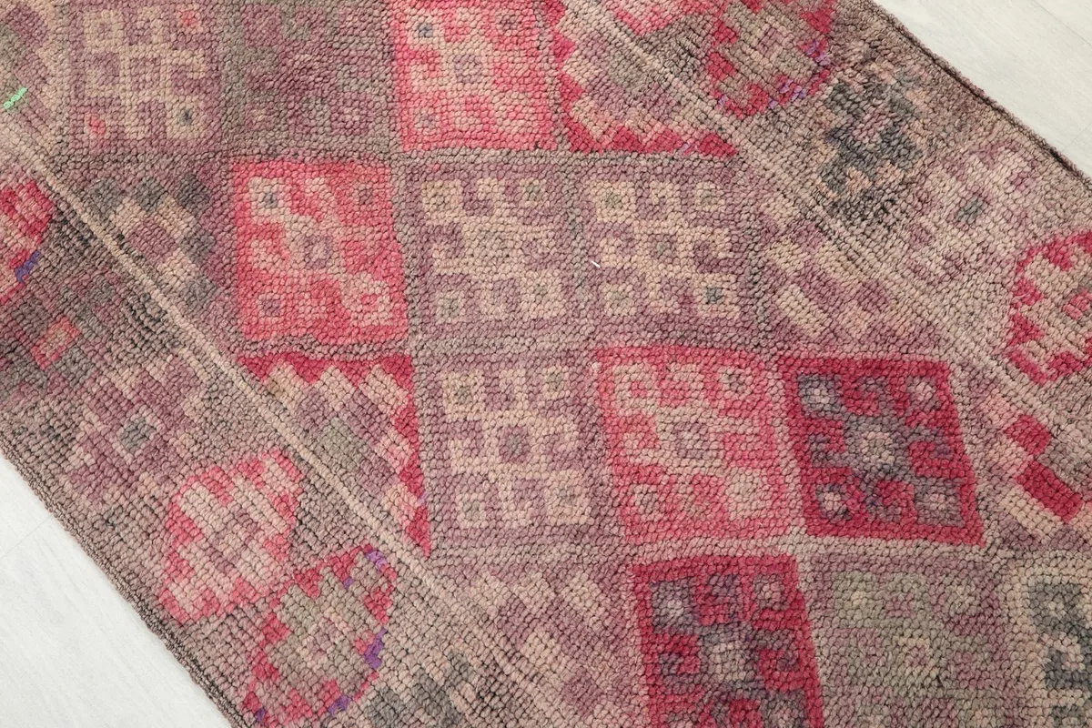 Close-up of the hand-knotted wool pile, highlighting the varied rose, beige, and gray tones