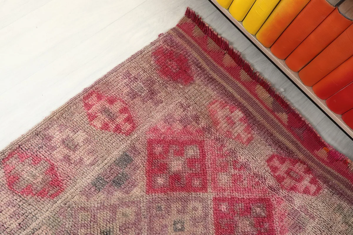 Detailed view of the rug's edge and part of the geometric design with red and gray accents