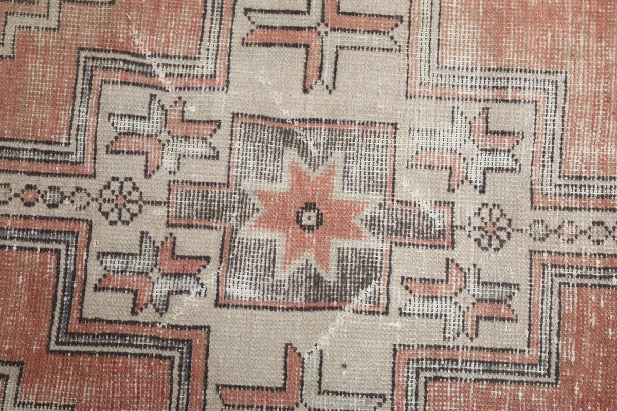 Close-up of the central star motif and geometric elements, showing the low pile and vintage wear.