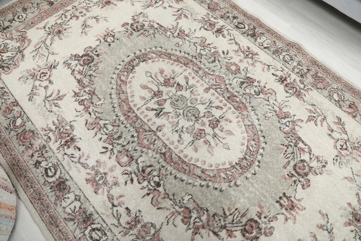 Angled view focusing on the central medallion and surrounding floral details on the ivory rug