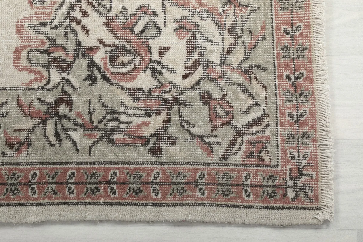 Close-up of the border and corner of the rug, highlighting rose and green floral patterns