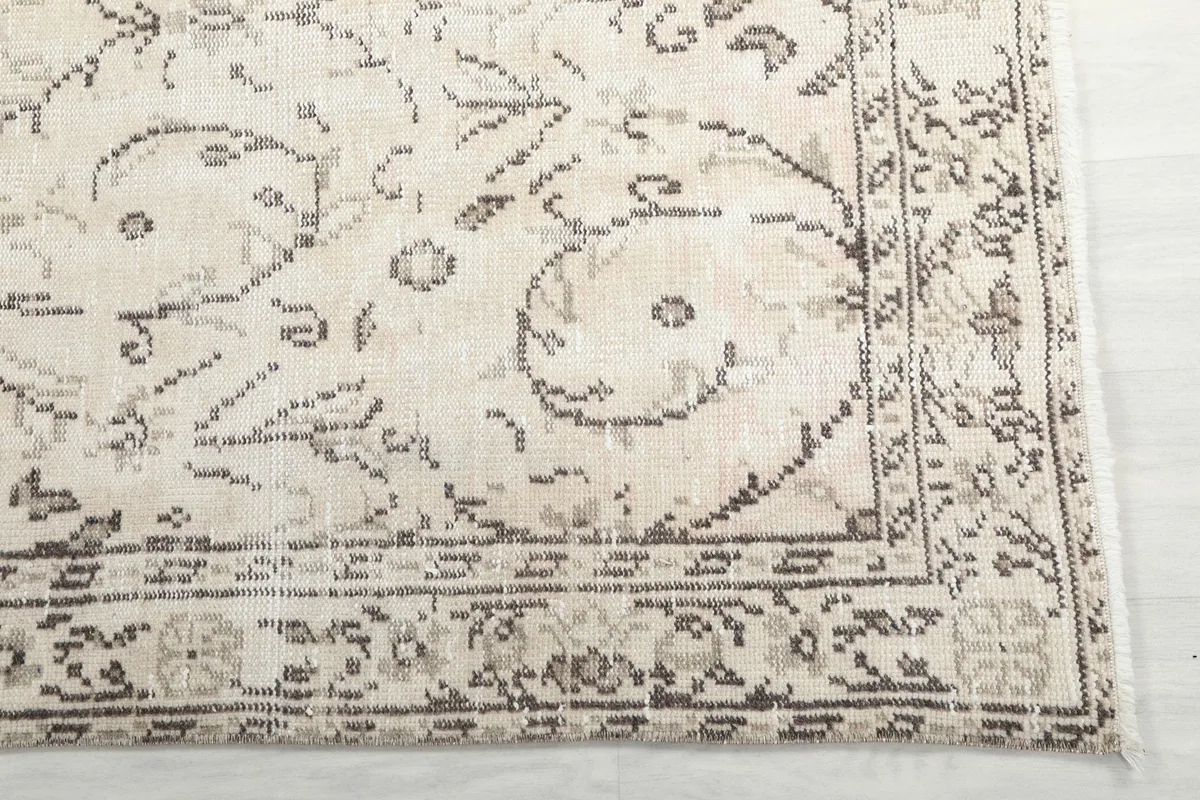 Detailed view of the rug's border and corner, showing the hand-knotted texture and gray patterns