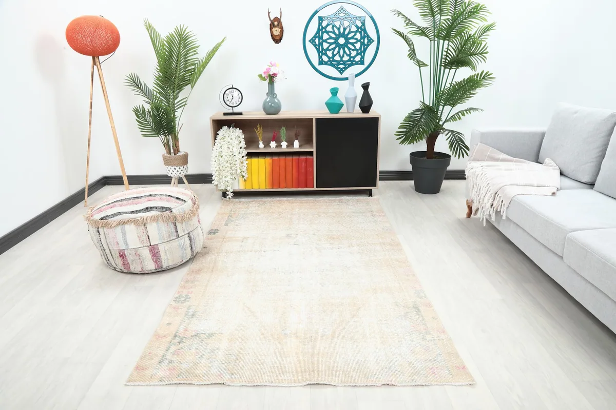 Vintage ivory and rose geometric rug placed in a living room setting, viewed from a distance.