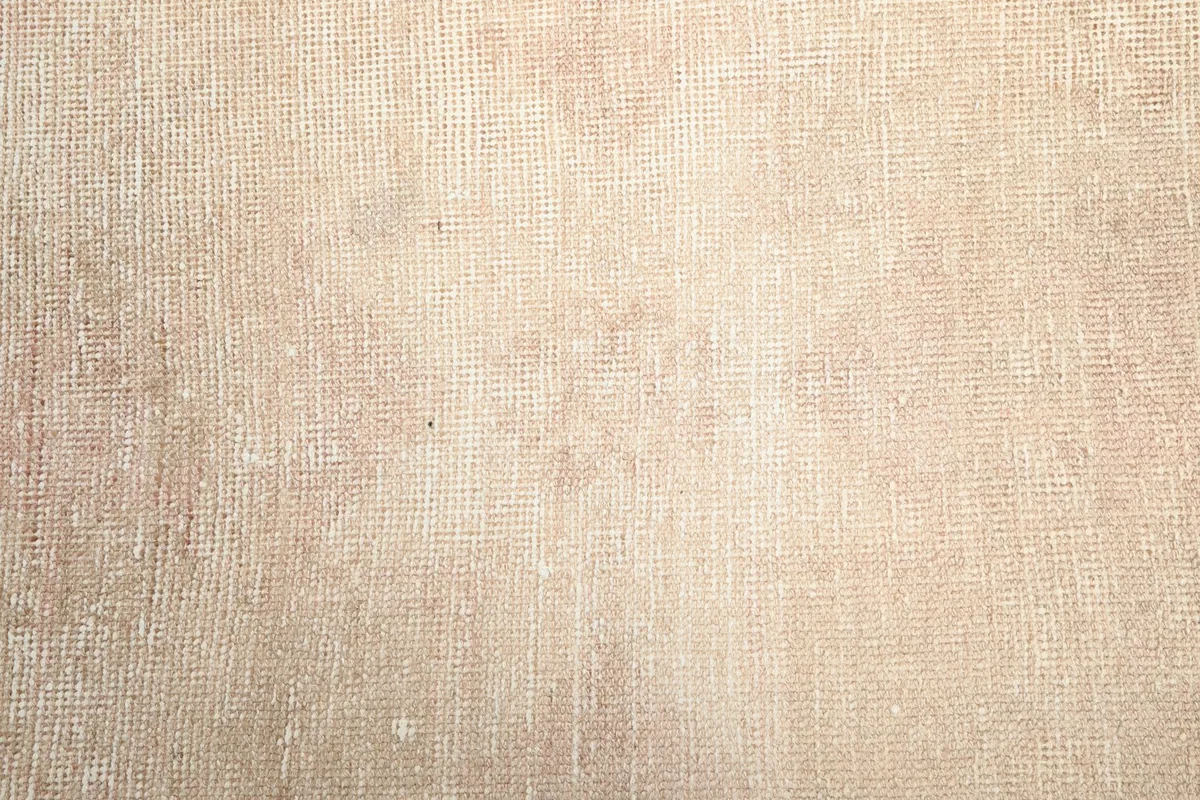 Detailed view of the rug's surface, revealing the hand-knotted texture and faded geometric patterns.