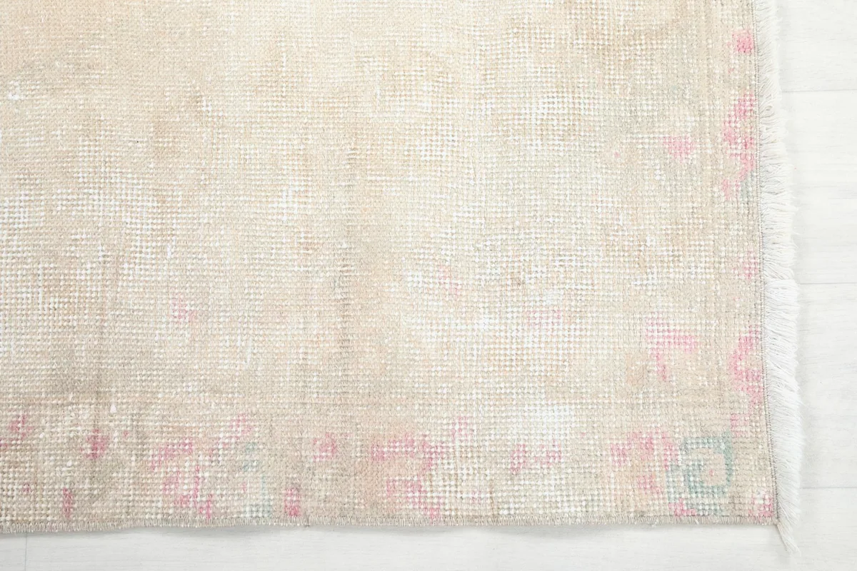 Detail of the rug's faded rose border and low pile texture