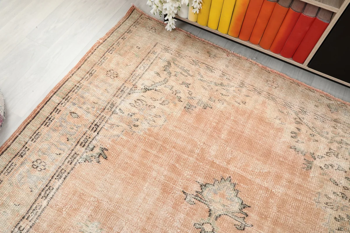 Overhead angled shot of the rug's upper section, showing the faded patterns and orange tones