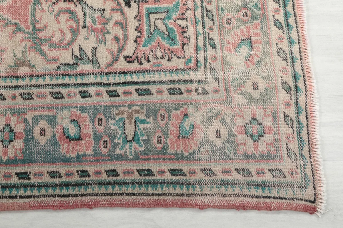 Detailed view of the corner of the rug, showing blue, green, and beige border patterns