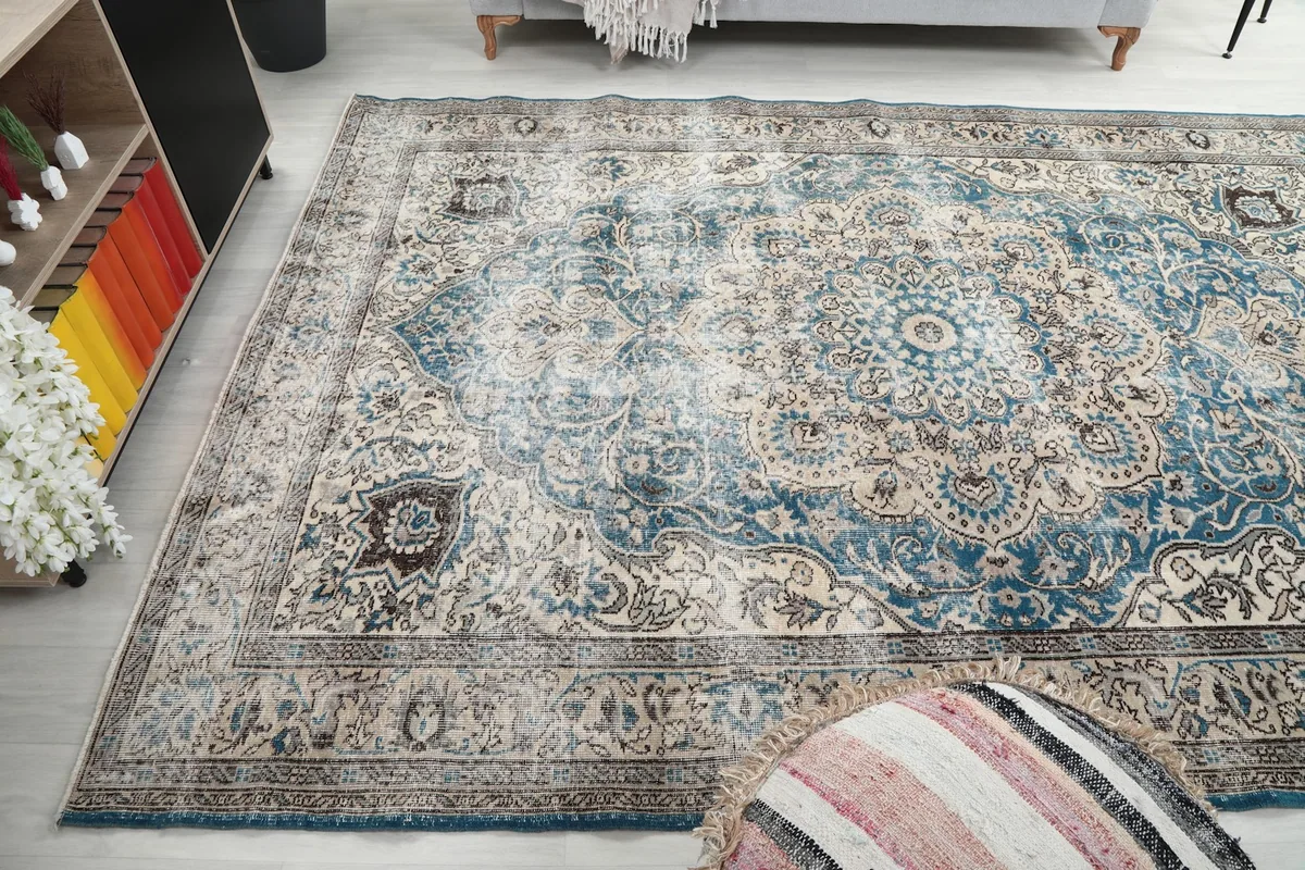 Wide shot of the rug in a living room, with a decorative pouf in the foreground
