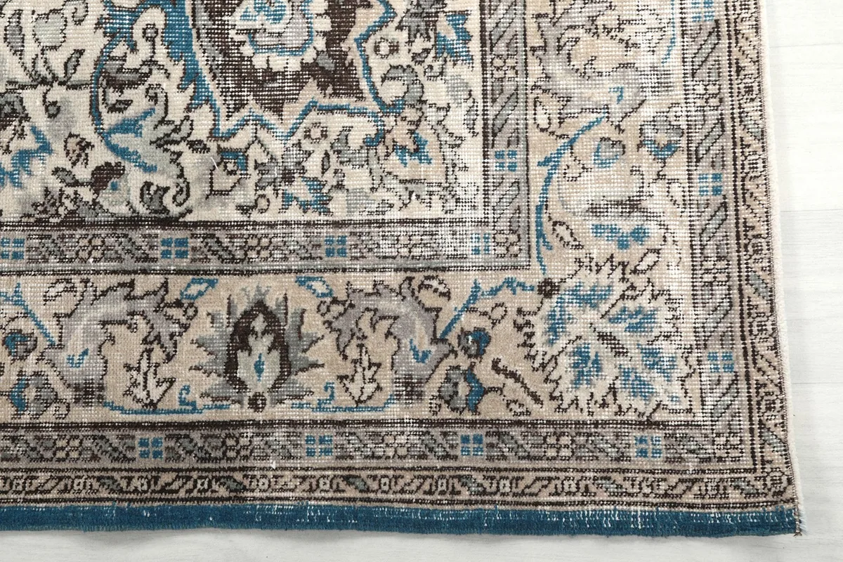 Detail of the rug's border pattern in beige, gray, and blue tones