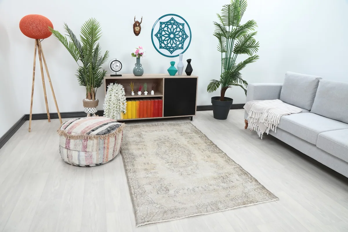 Angled view of the beige and gray Anatolian rug in a room, showing its placement relative to a sofa