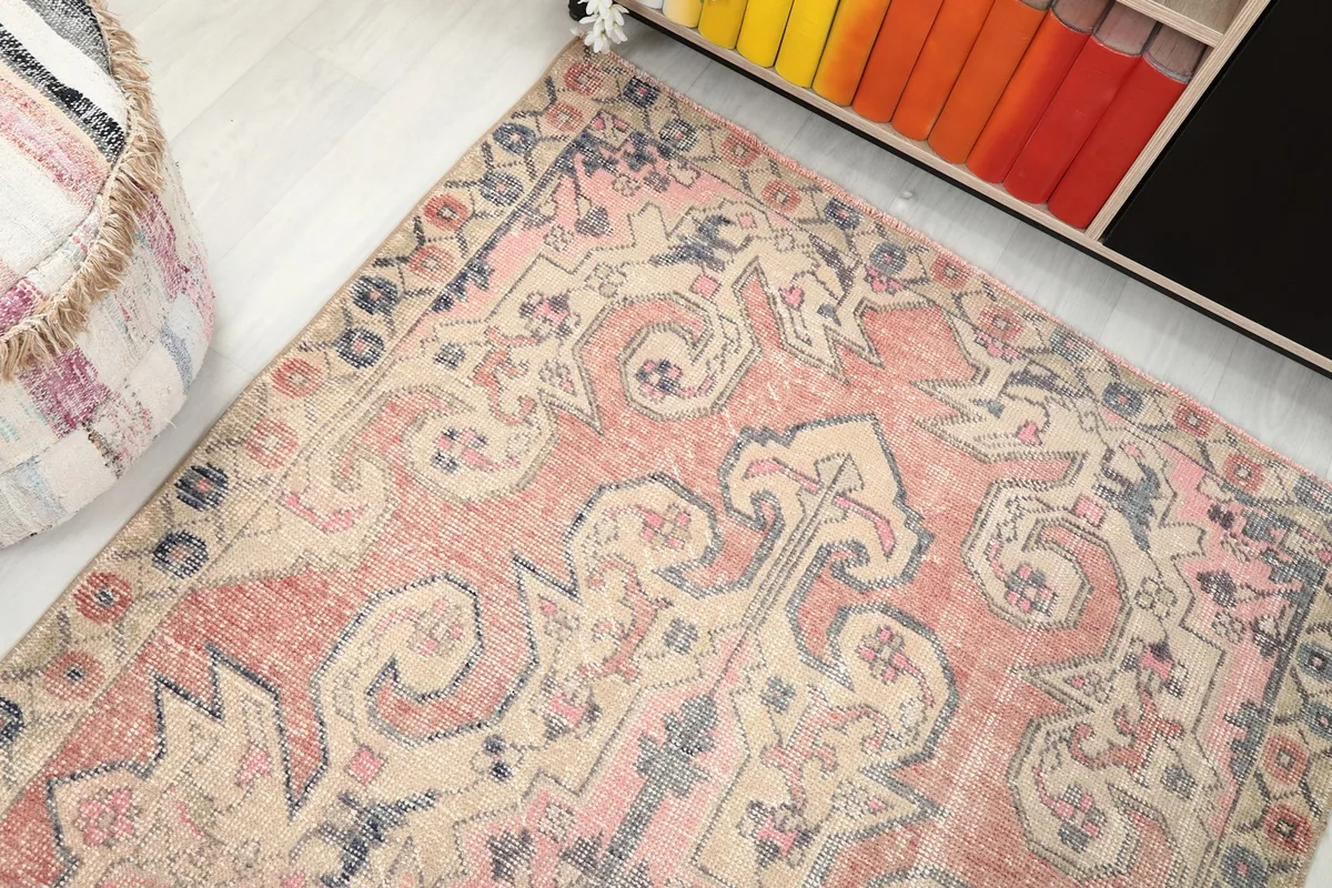 View of the rug from above, capturing the blend of rose, rust, beige, and navy tones
