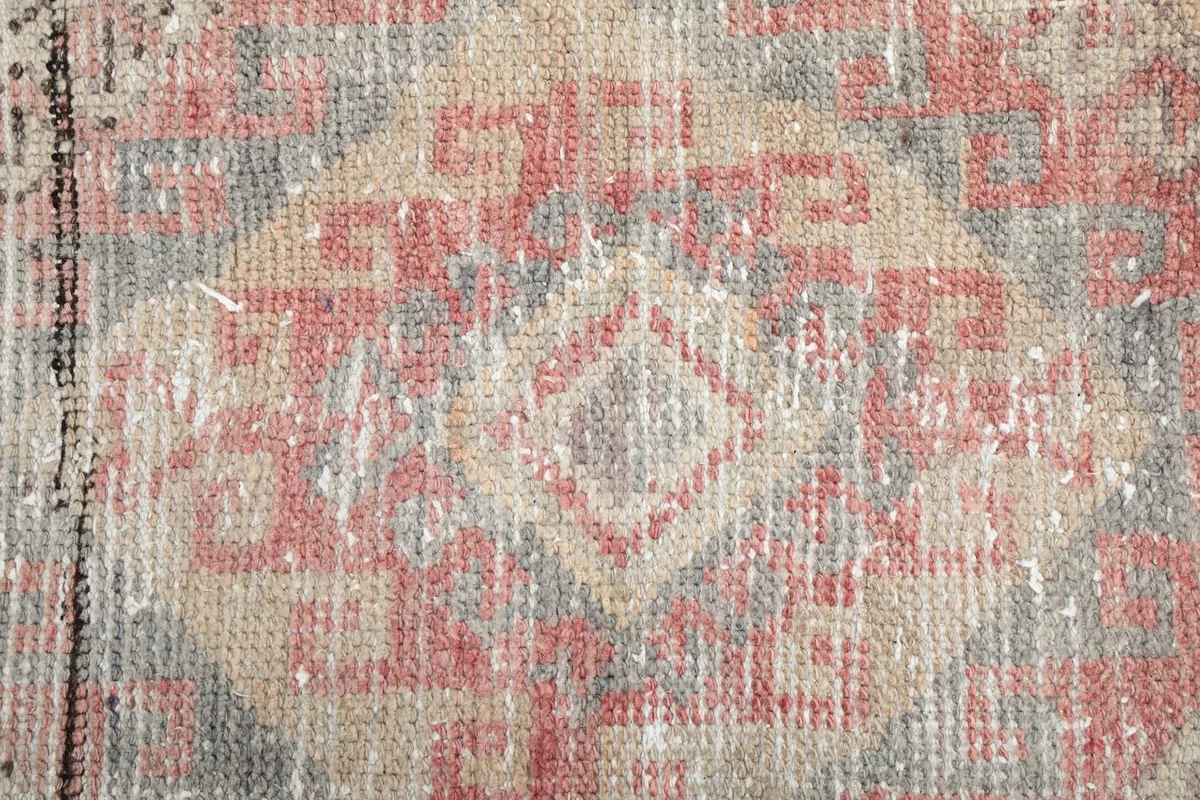 Close-up of the rug's low wool pile, revealing the distressed texture and color variations