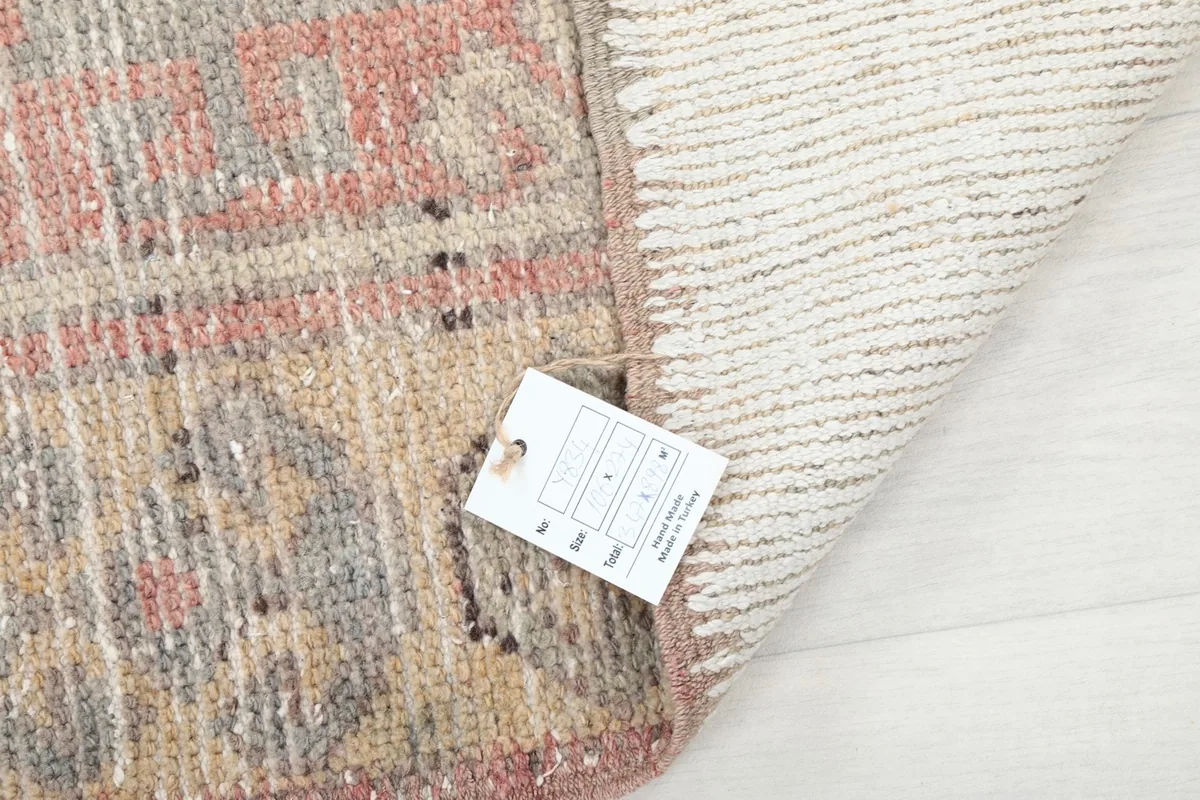 Corner of the rug with a product tag, displaying the hand-knotted wool on cotton foundation