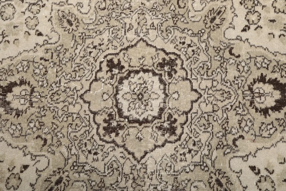 Close-up of the central medallion design with intricate charcoal floral details on an ivory field
