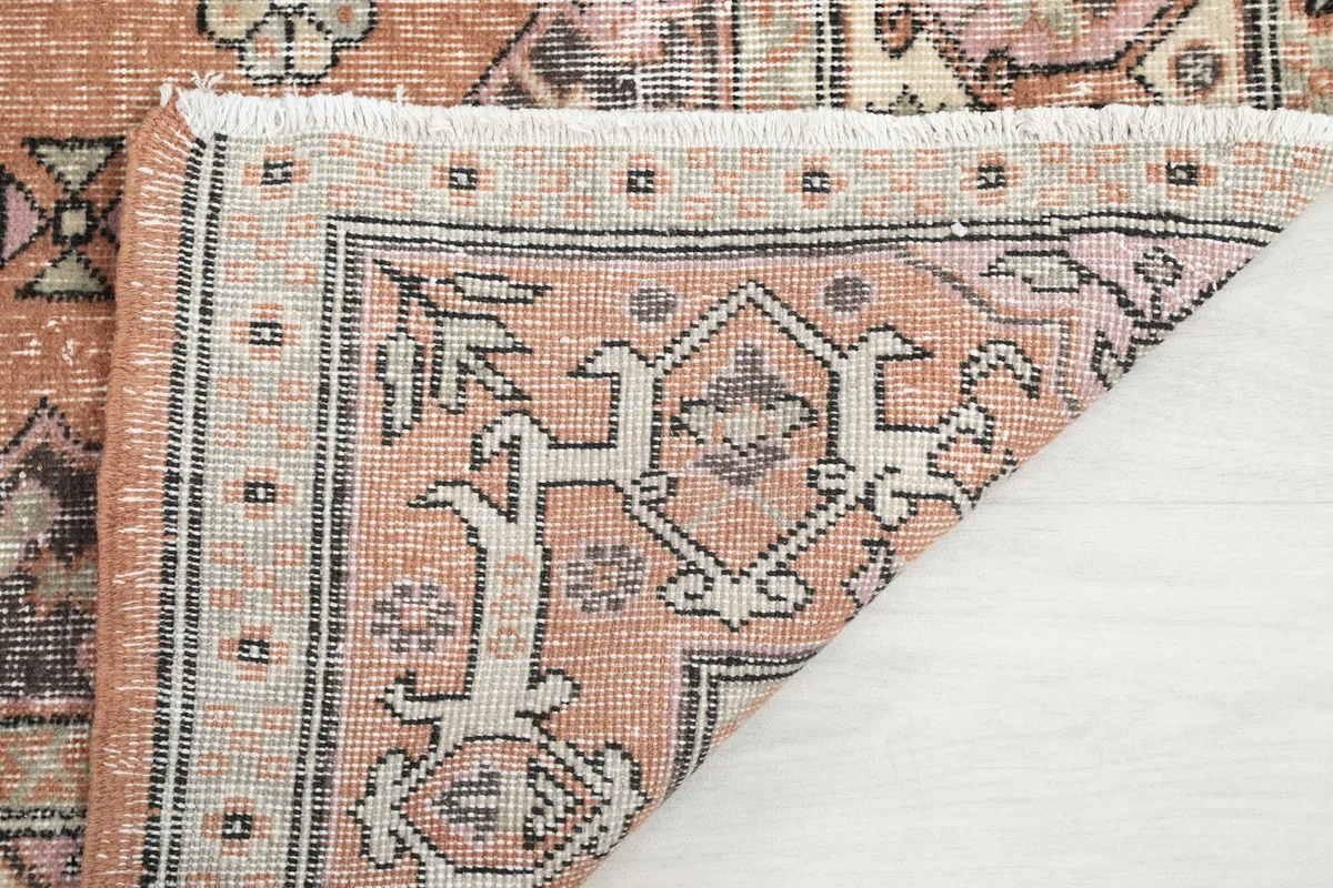 Corner of the rug turned over to display the hand-knotted cotton foundation
