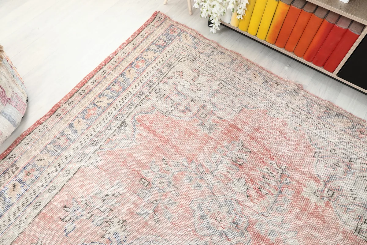 Overhead angle shot of the rug's corner and patterns near a bookshelf