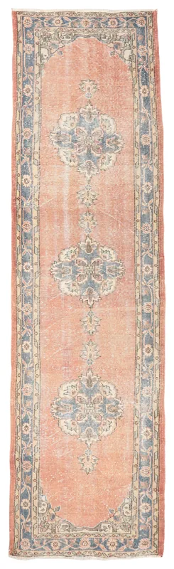Full overhead view of the rust and blue vintage runner rug on a white background.