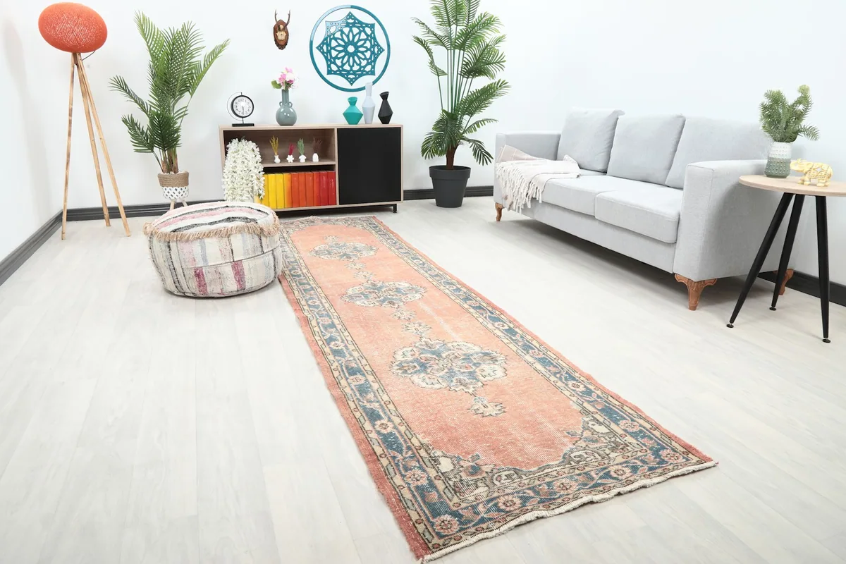 Angle view of the rust and blue runner rug extending from a seating area into a hallway.