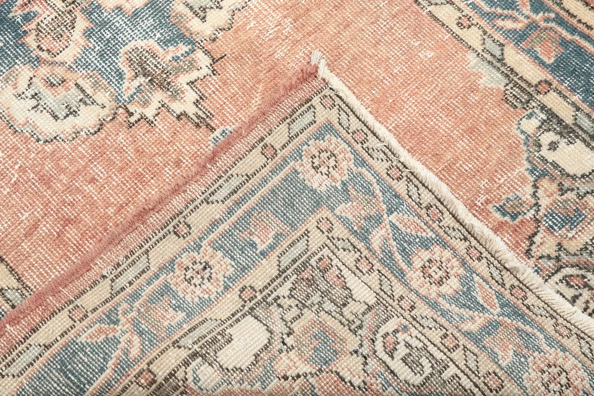 Close-up of the rug's pile and knotting, showing the vintage wear and color variations in the corner.