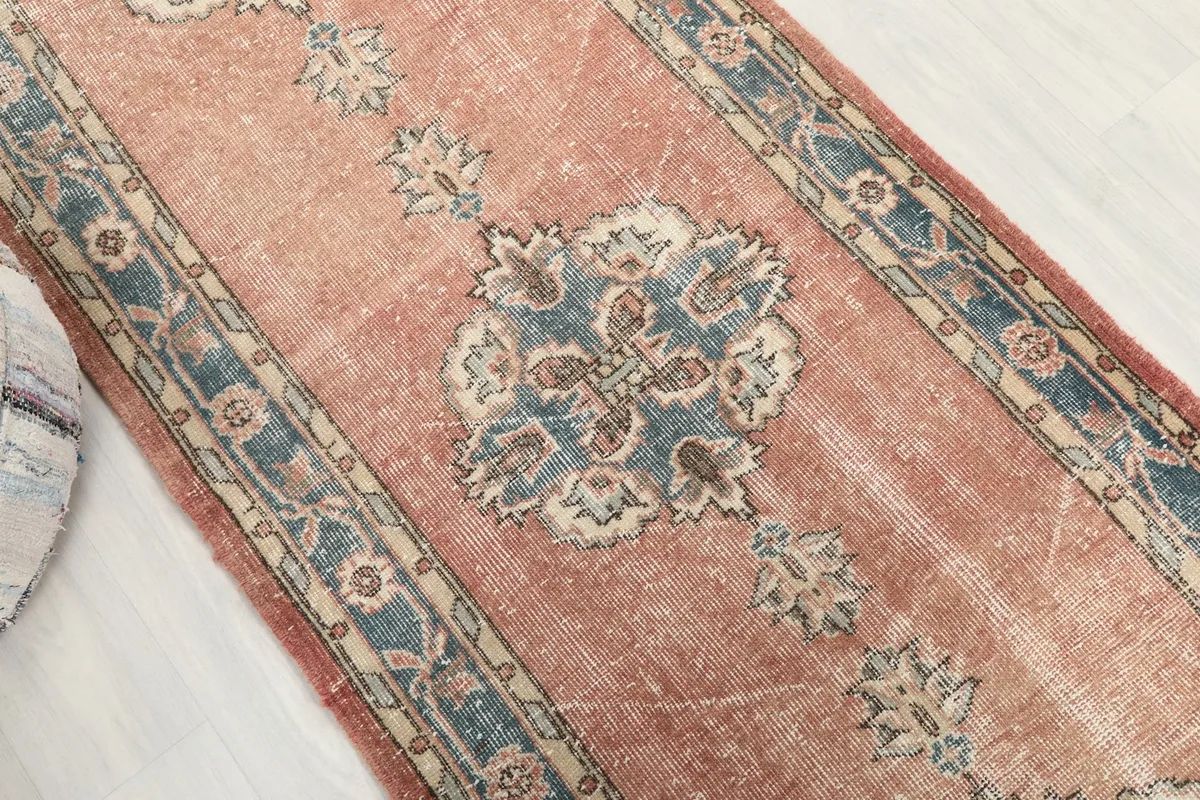 Overhead view focusing on a central blue medallion and surrounding rust field of the runner rug.