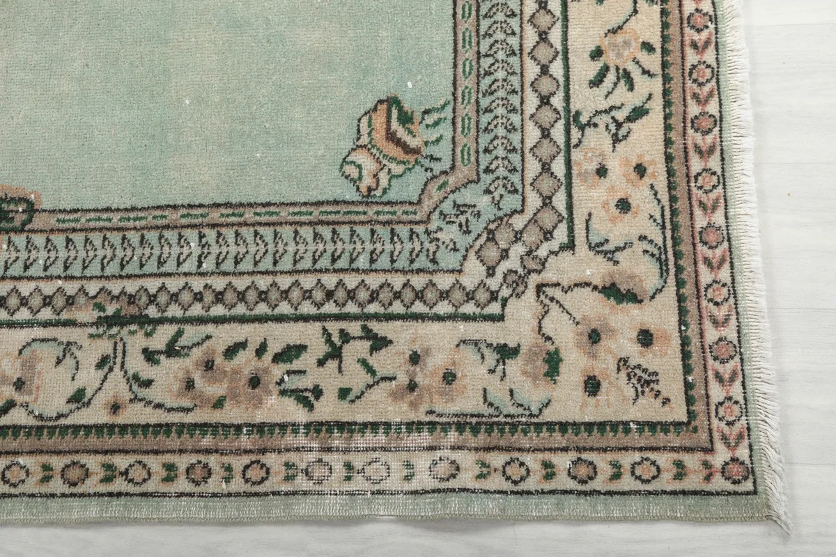 Detail of the Faded Green Floral Medallion Rug's intricate border design and fringe.