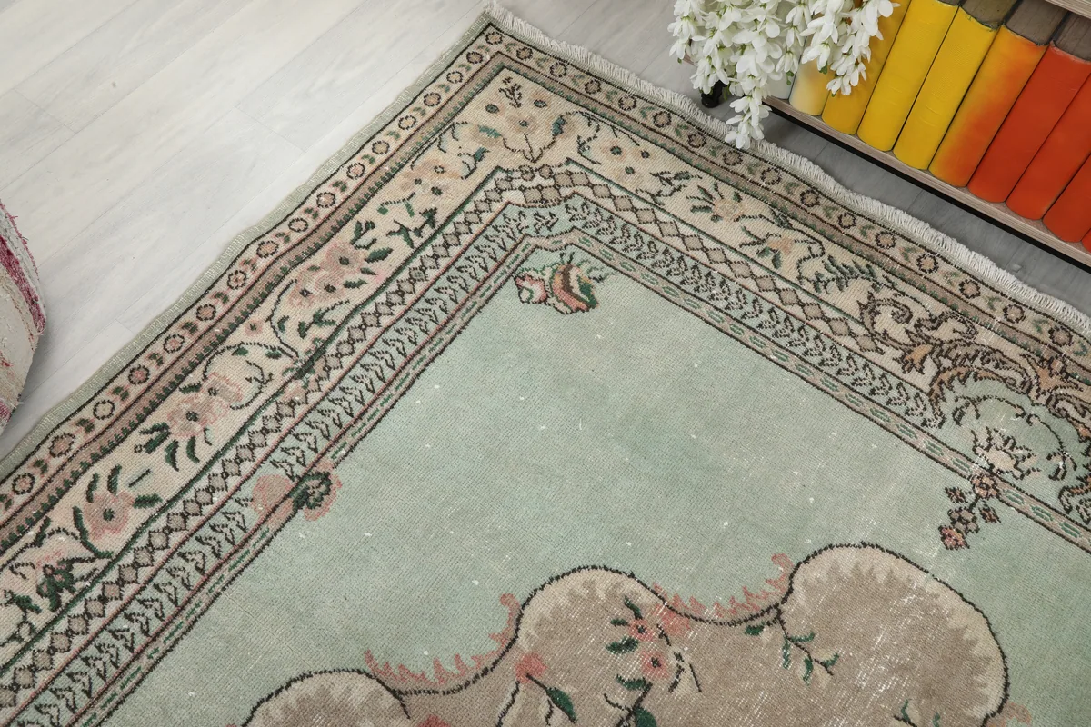 Detailed view of a corner of the Faded Green Floral Medallion Rug, showing border patterns and color variations.