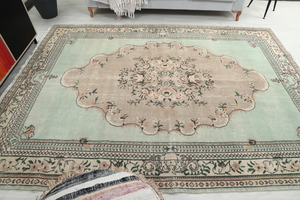 Faded Green Floral Medallion Rug viewed from another angle in a room, highlighting its overall design.