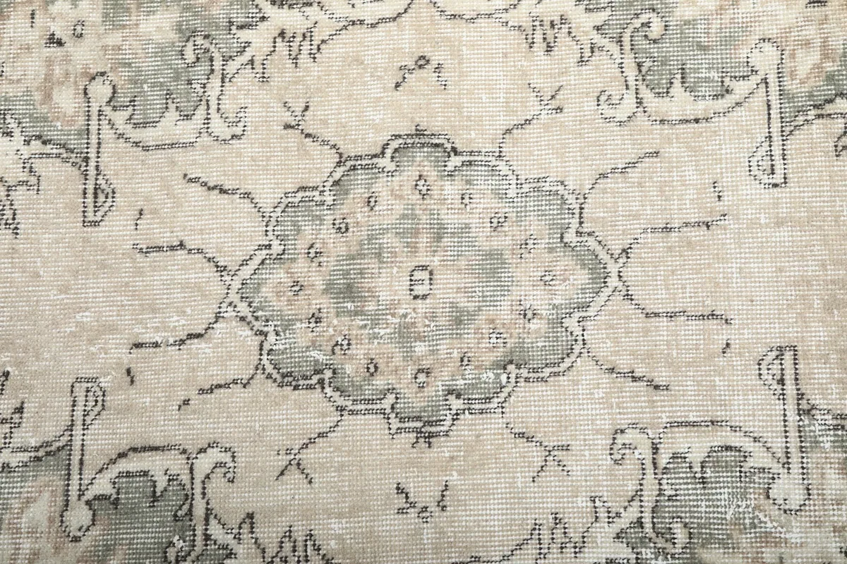 Close-up of the central medallion pattern with green, beige, and gray tones.