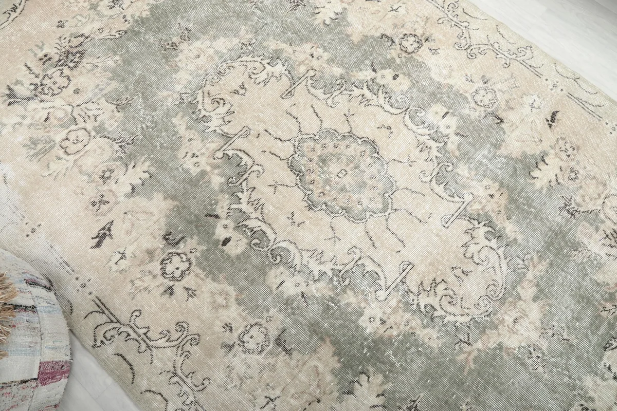 Overhead view focusing on the central green medallion and the distressed texture of the rug.
