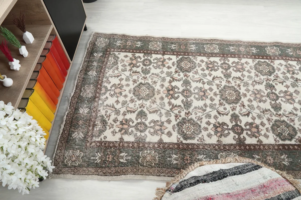 Angled view of the rug's surface, showing the ivory field and green border