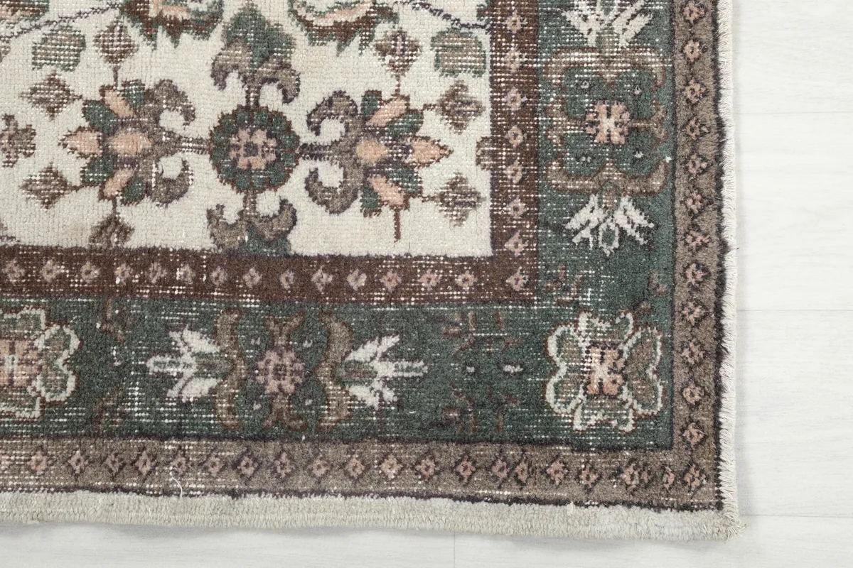 Close-up detail of the rug's corner, highlighting the green and brown border patterns