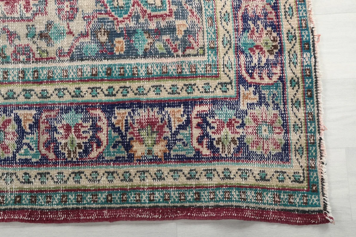 Close-up detail of the intricate navy and beige border pattern of the vintage rug