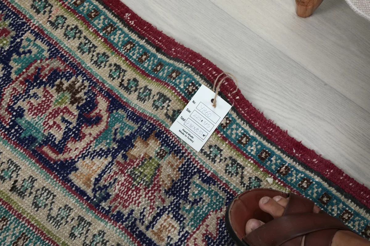 Close-up of the low wool pile and a foot for scale, with product tag visible