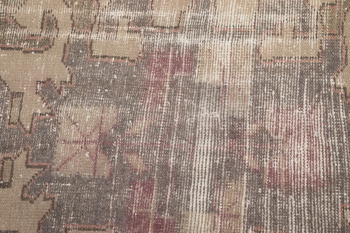 Close-up showing the low pile and distressed areas of the vintage wool rug