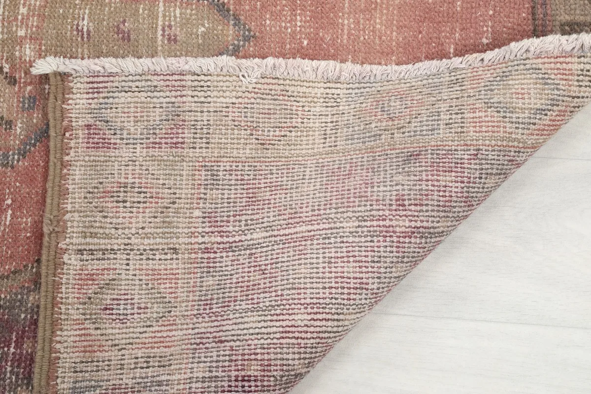 Close-up of the rug's edge, showing the back and the short, aged fringe