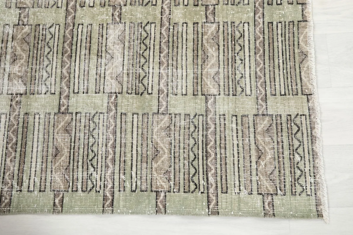 Detailed view of the olive field and brown geometric motifs on the vintage rug