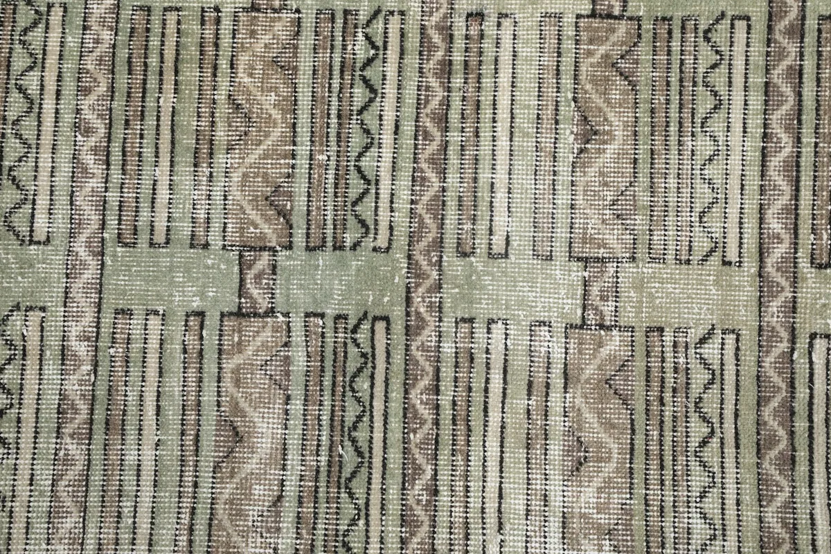 Close-up of the hand-knotted texture and geometric designs in olive and brown