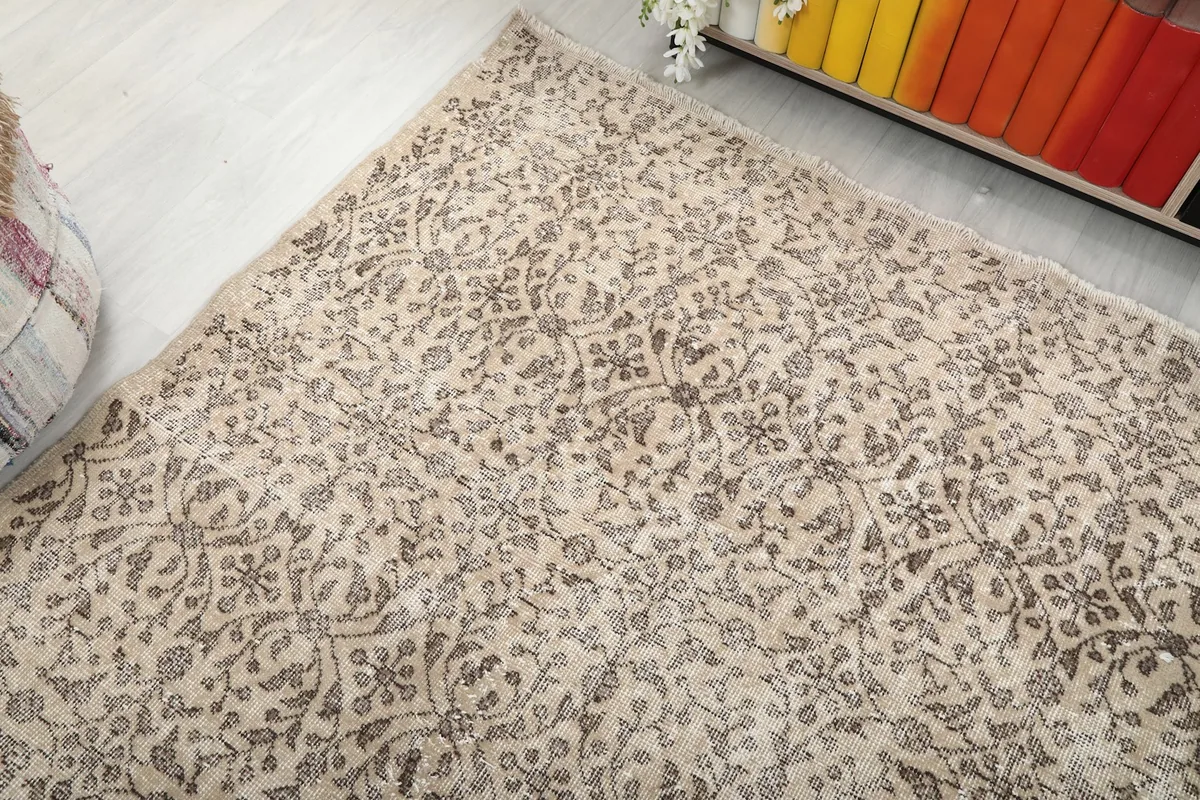 Corner view of the rug on the floor, showing its placement relative to a decorative pouf.