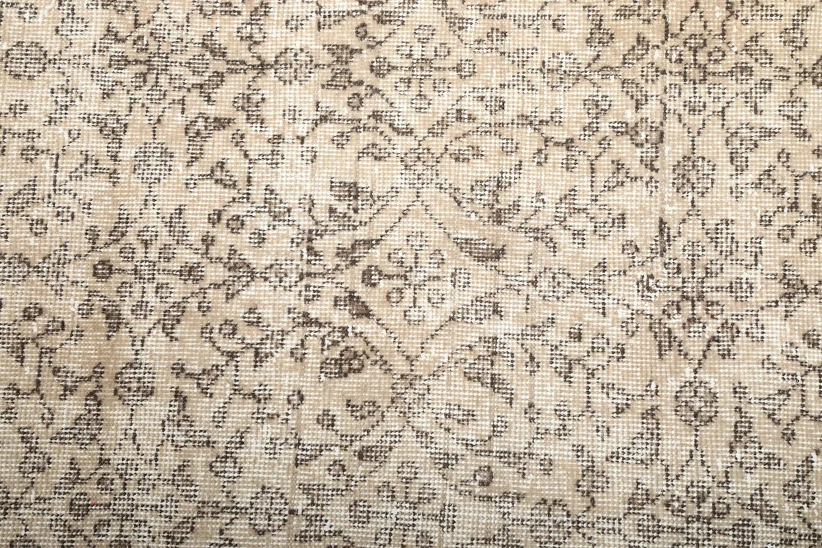 Close-up of the vintage rug's pile, revealing the detailed floral design and subtle color variations.