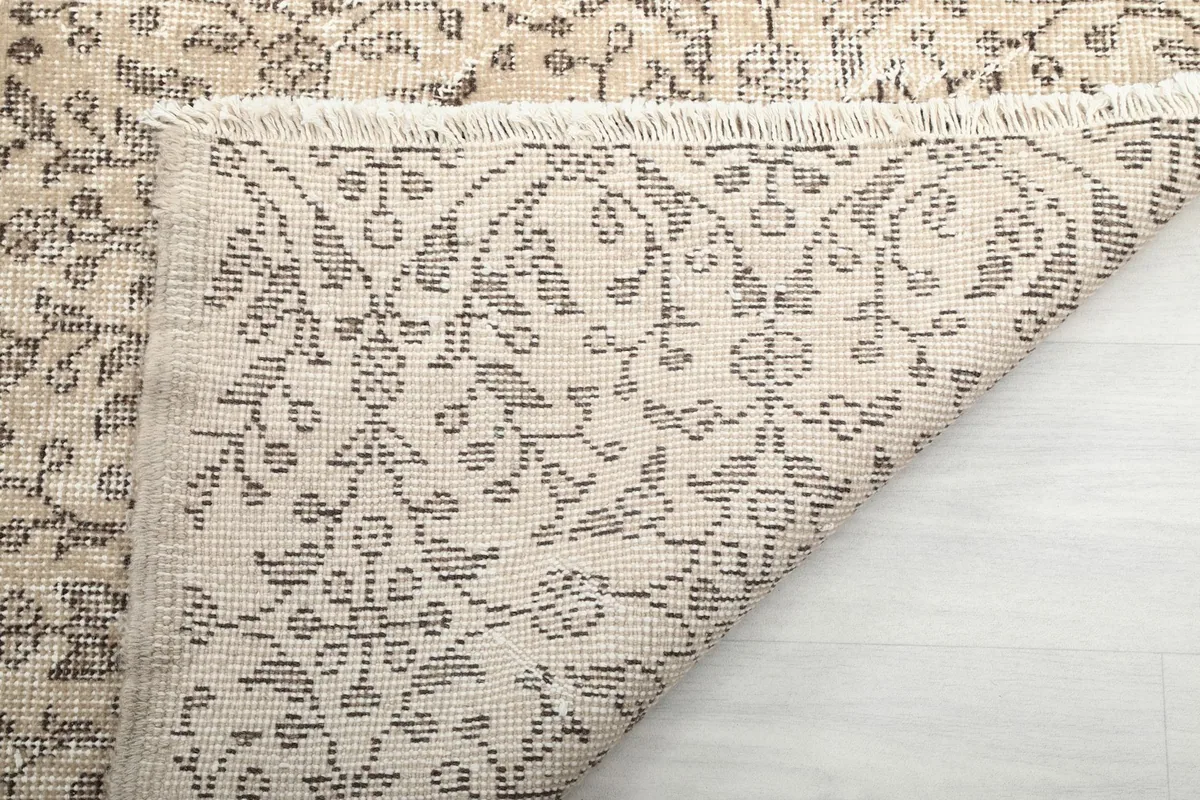 Close-up of the back of the rug, showing the hand-knotted cotton foundation and wool pile knots.