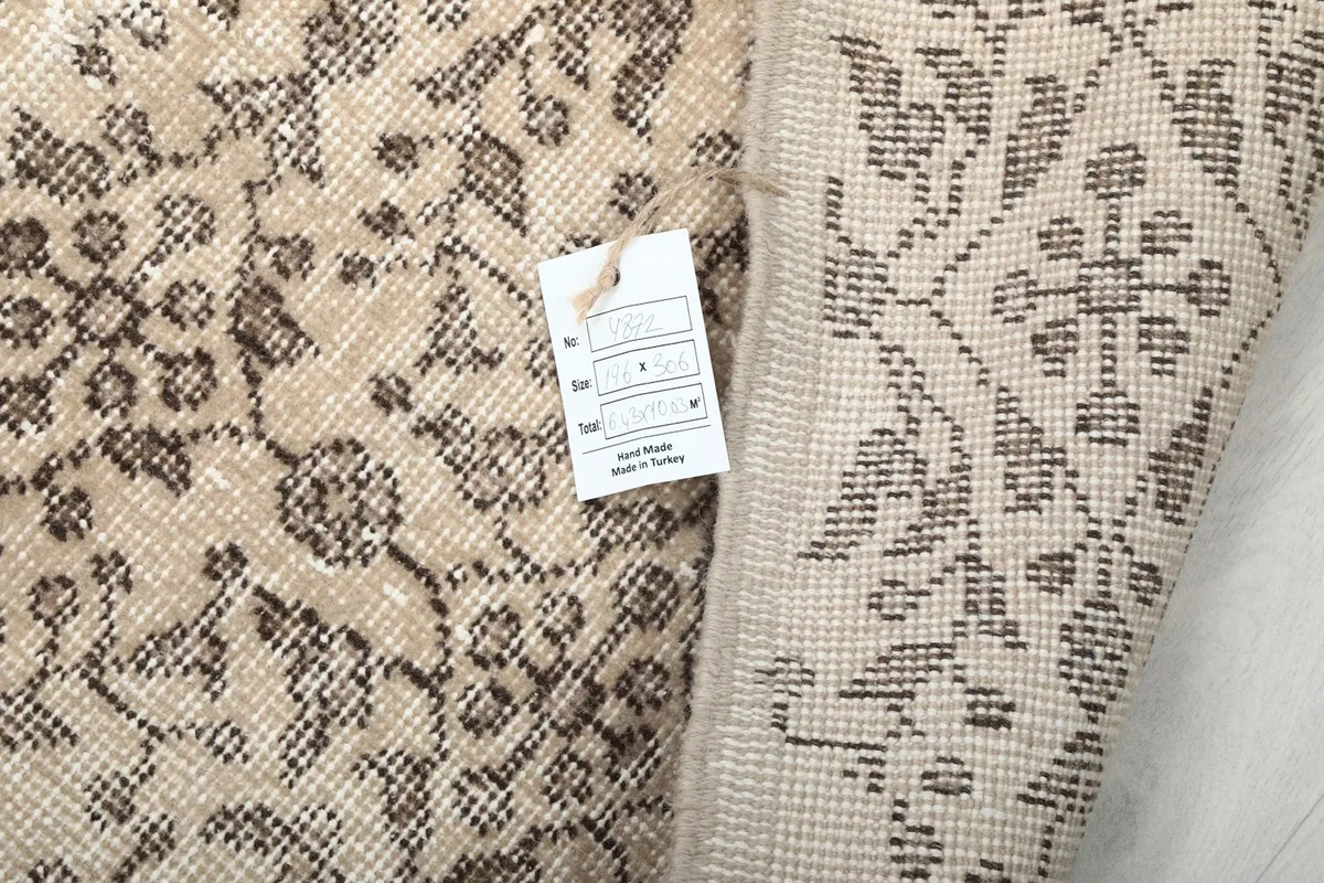 A tag attached to the rug's corner, indicating its hand-knotted origin and material.