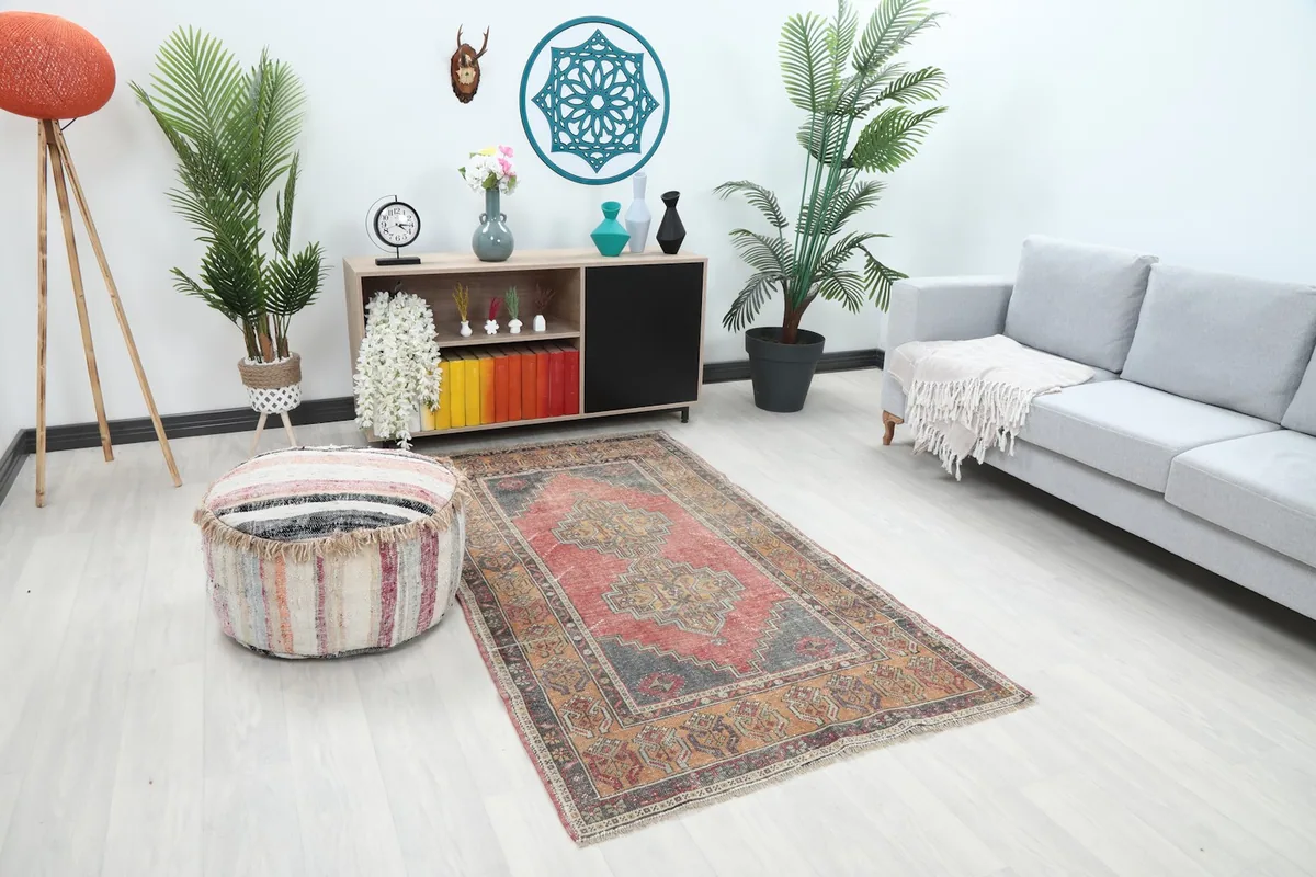 Angle view of the rose and gray rug in a living room with a sofa and pouf
