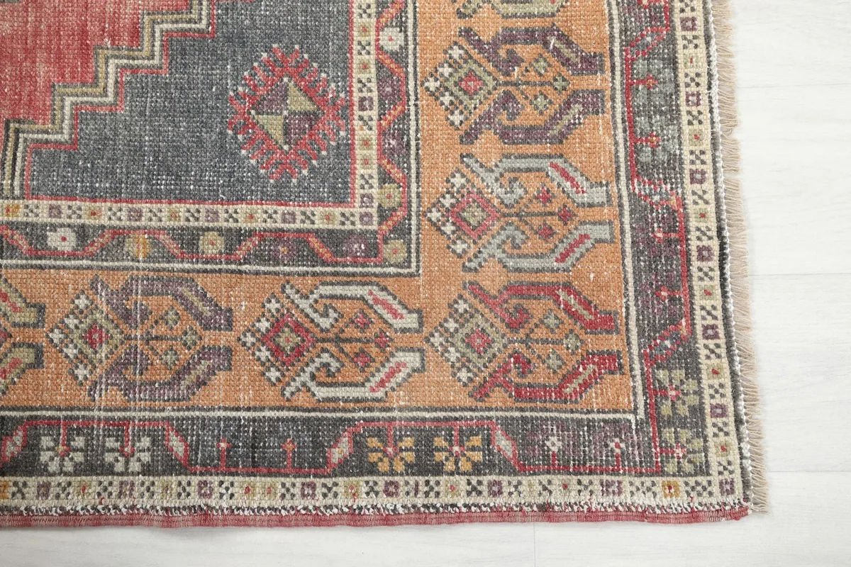 Detailed view of the orange border and corner patterns of the vintage rug