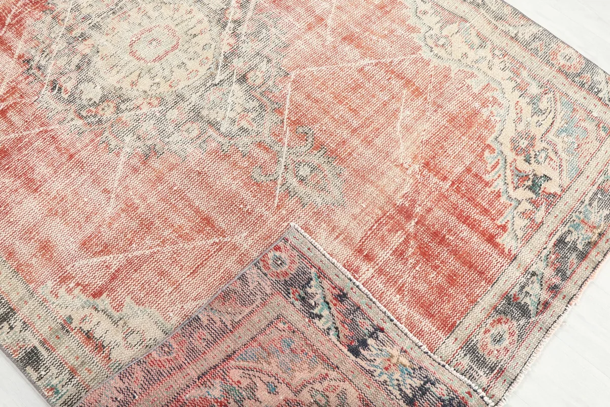 Corner of the rug folded back to reveal the back weaving and a glimpse of the border.