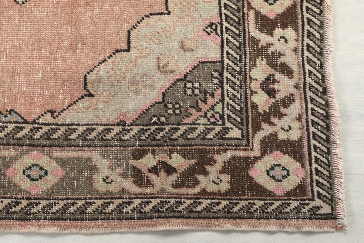 Detail of the rug's border with intricate brown, beige, and black geometric patterns