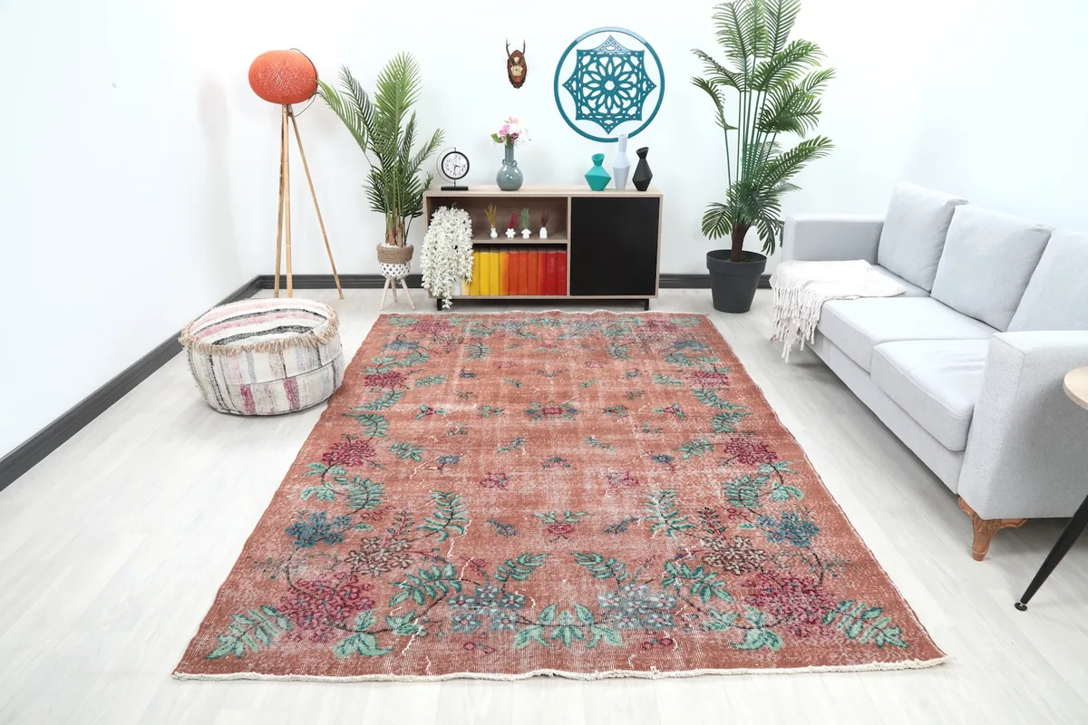 Rust floral vintage rug in a living room setting with a gray sofa and wooden cabinet
