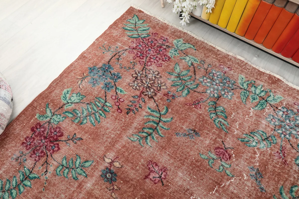 Corner detail of the rug's floral border with green leaves and rose blossoms