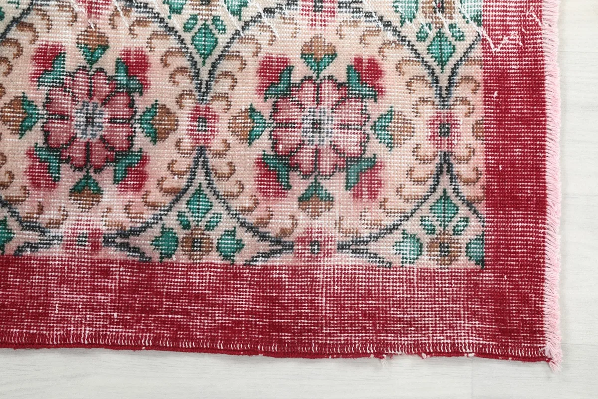 Detail of the distressed red border and a corner of the cream field with rose motifs